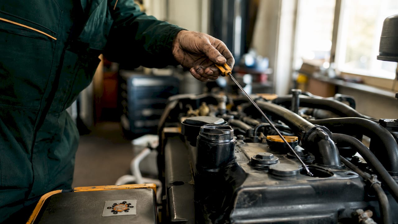 Un tehnician verifică nivelul uleiului la un motor Perkins, afară, la lumina naturală.