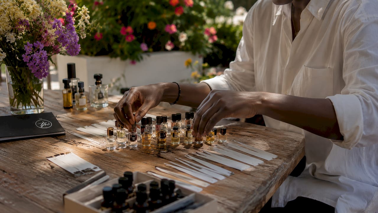 Close-up of hands arranging perfume samples on vanity