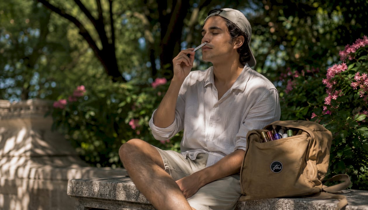 Man testing fragrance strip in sunny city park