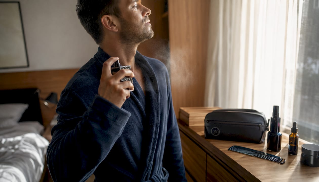 Man spraying perfume after shower in bathroom