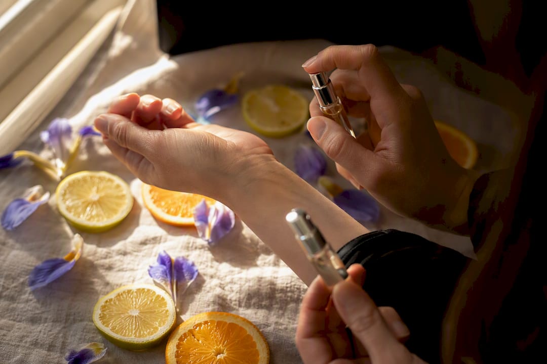 Spraying layered perfume samples on wrist with citrus and iris