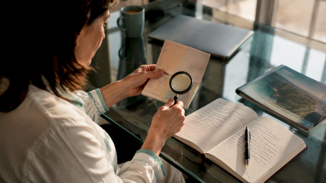Hands examining passport with magnifying glass