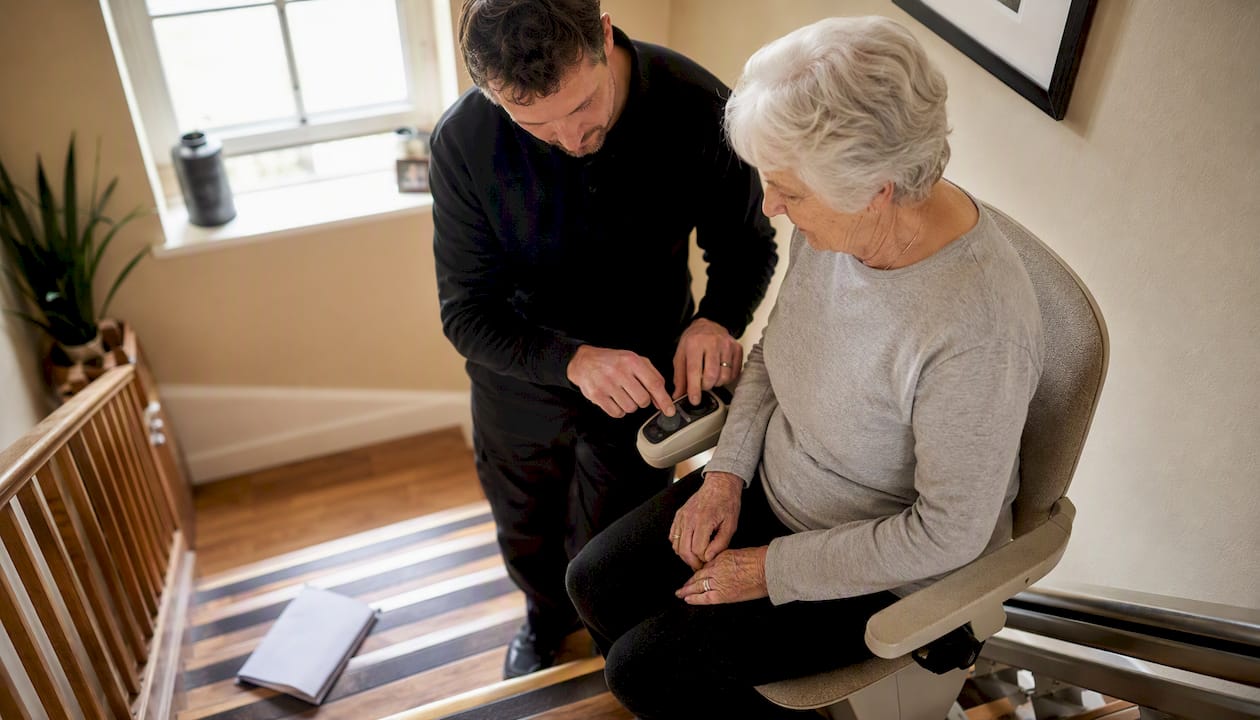 Technician showing stairlift controls to elderly user