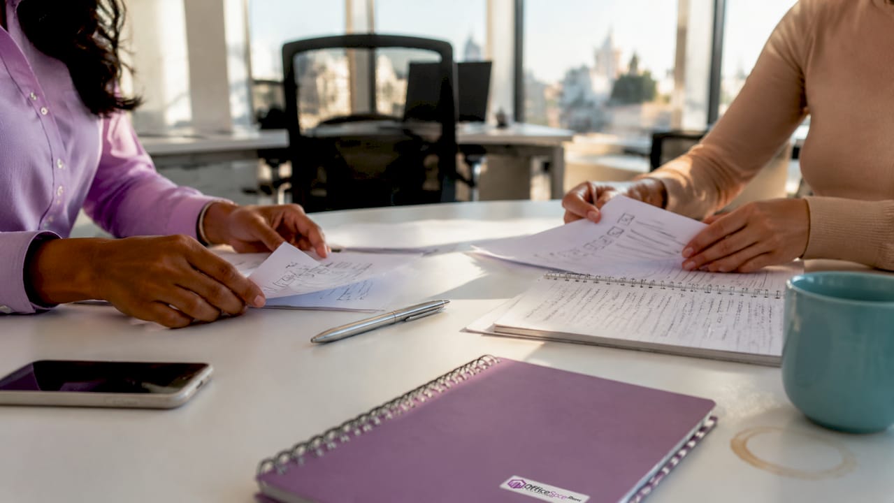 Overhead of hands and onboarding paperwork on desk