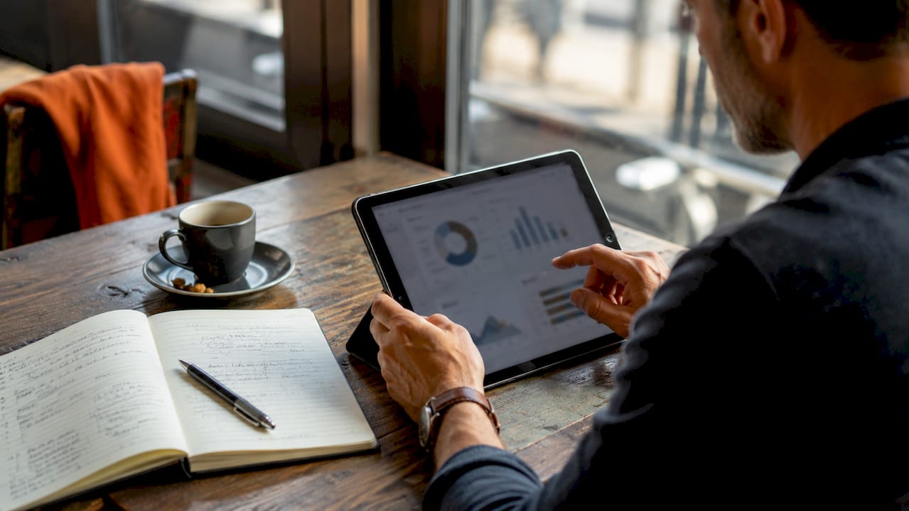 Mit dem Tablet im Café werden gerade KPIs analysiert.