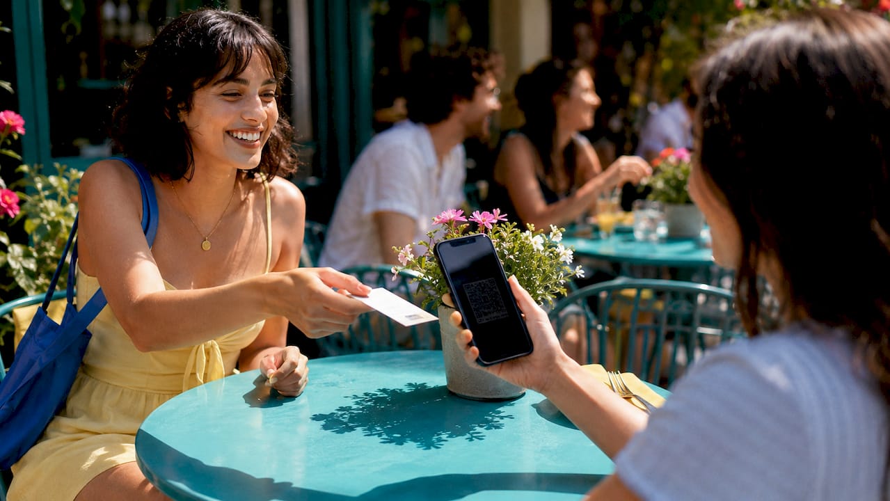 Hands exchanging coupon and smartphone at restaurant table