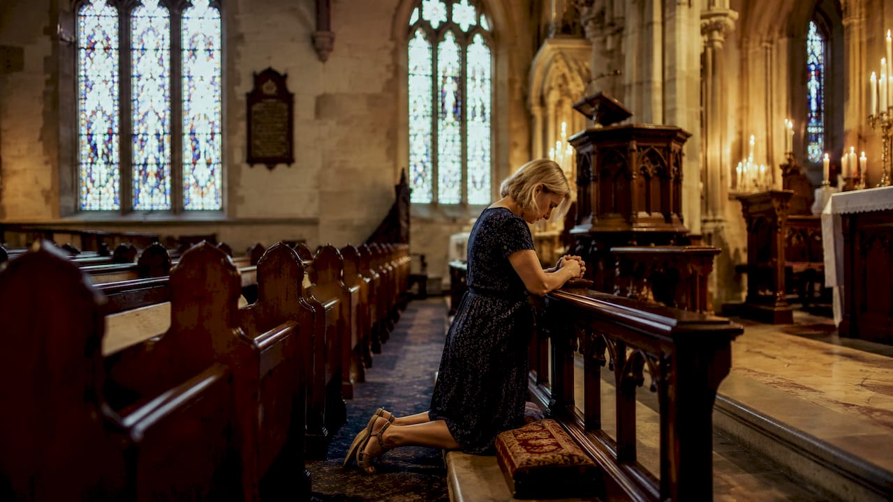 Woman praying inside heritage Anglican church interior