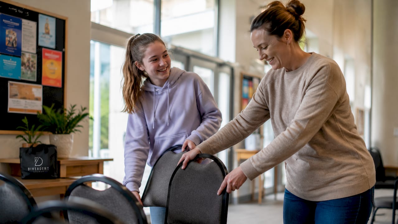 Teen and adult setting up church hall together