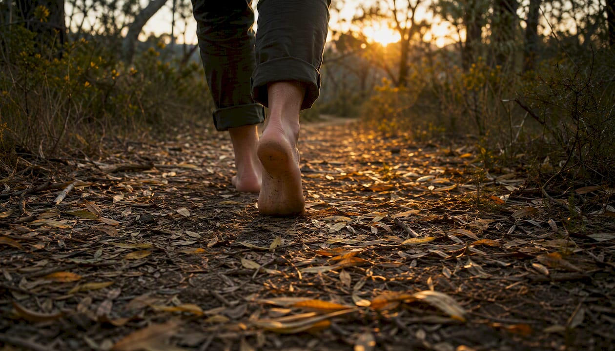Feet walking contemplatively on leafy path