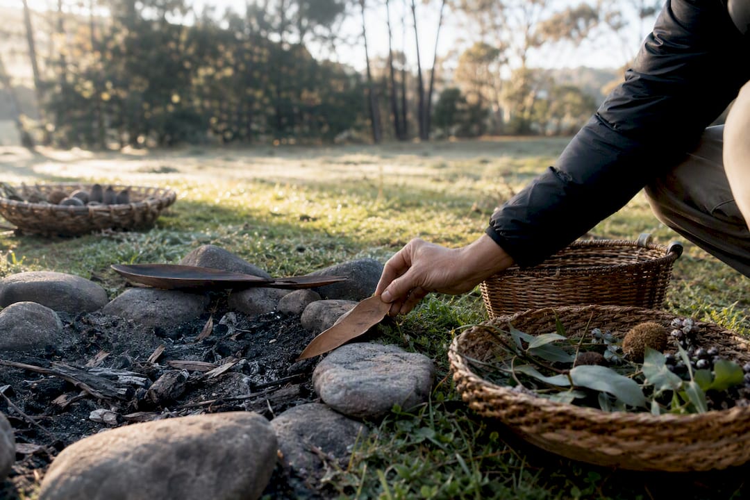 Hand placing seed pod in indigenous ceremony setting