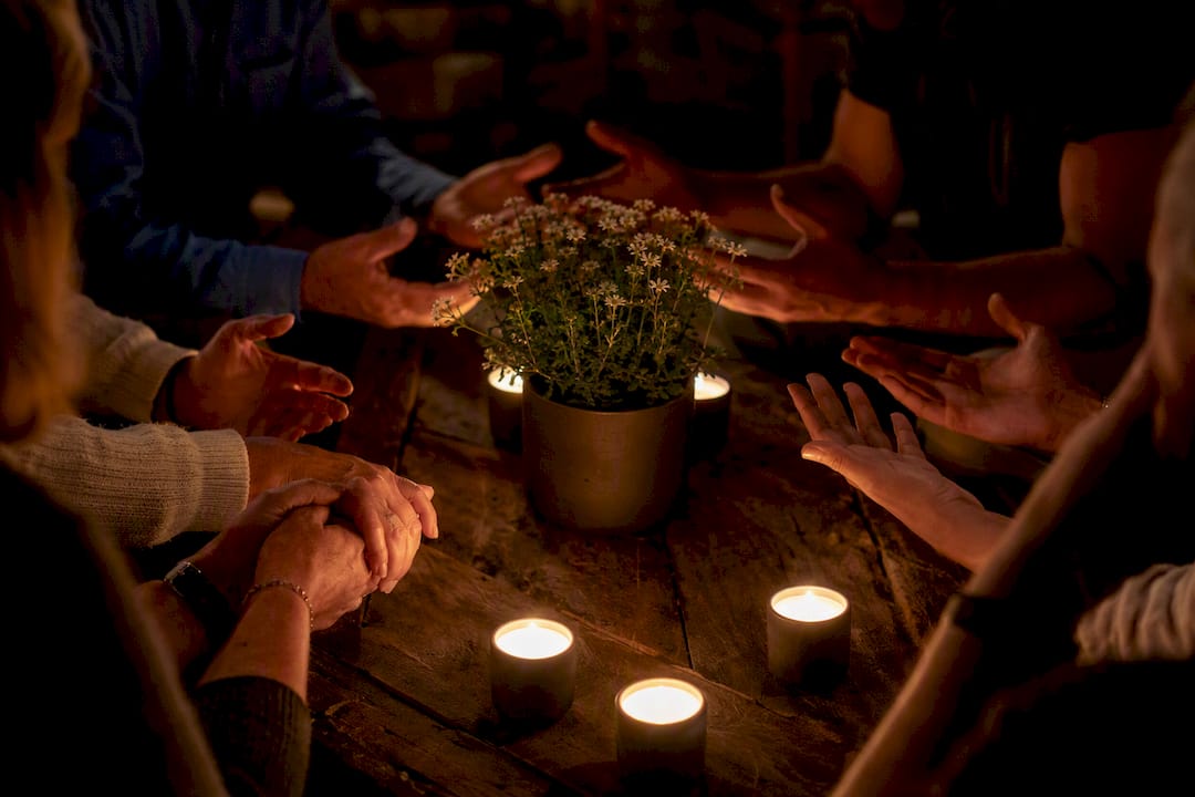 Hands joined in prayer around candle