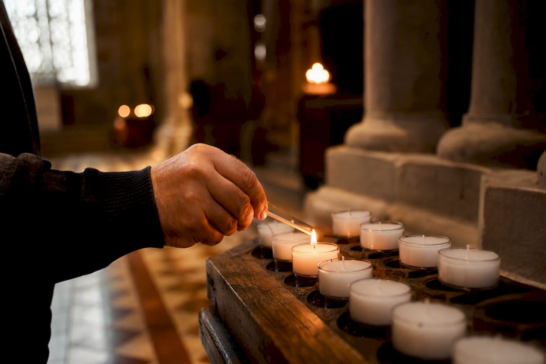Hand lighting votive candle in church