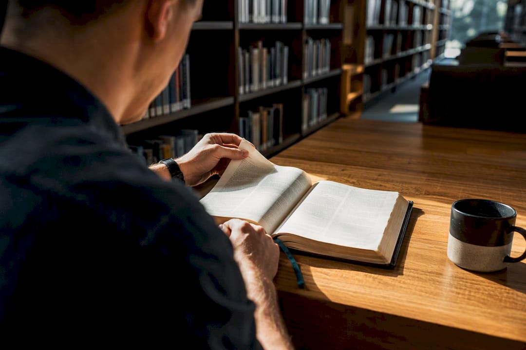 Hands reading Bible in quiet church library