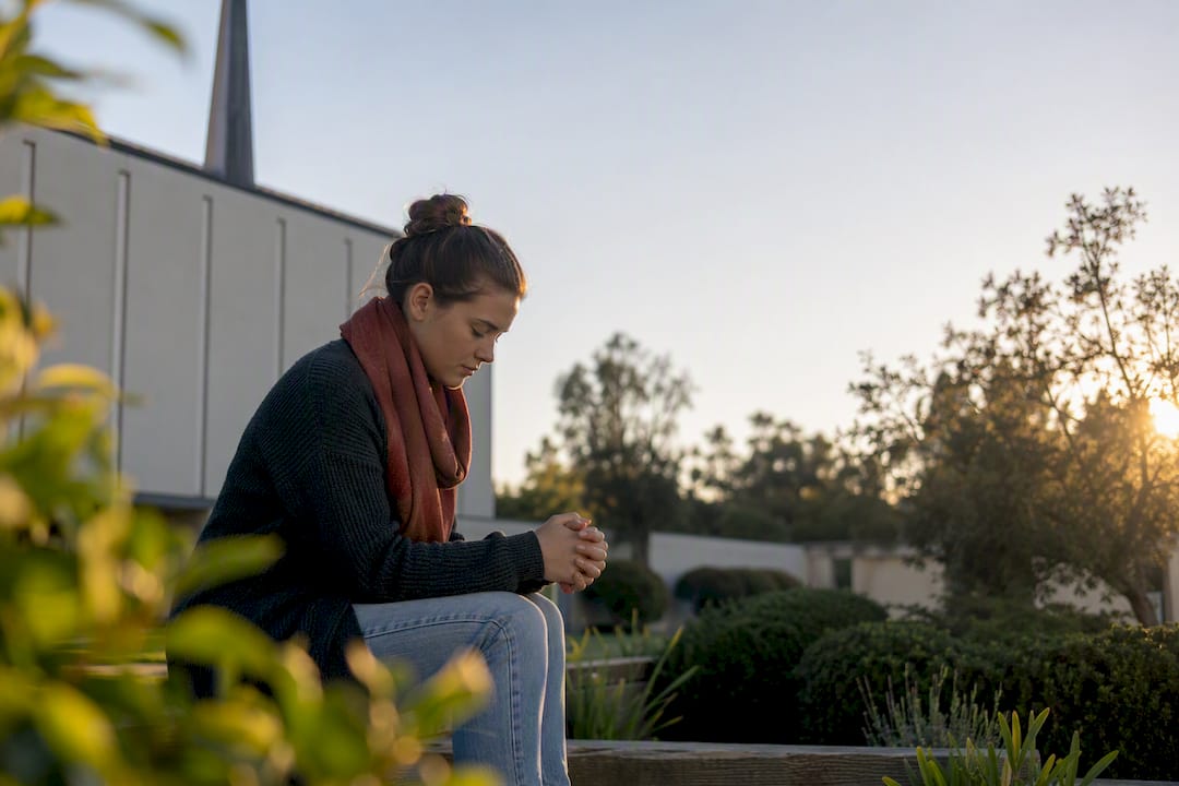 Person praying quietly in a Canberra church garden