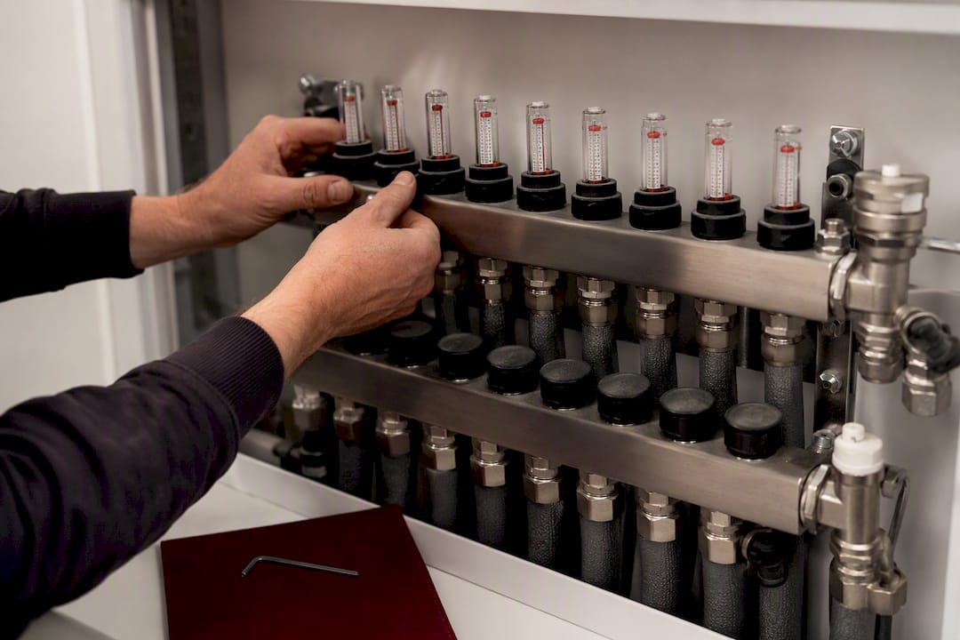 Installateur kontrolliert die Durchflussanzeigen am Heizkreisverteiler