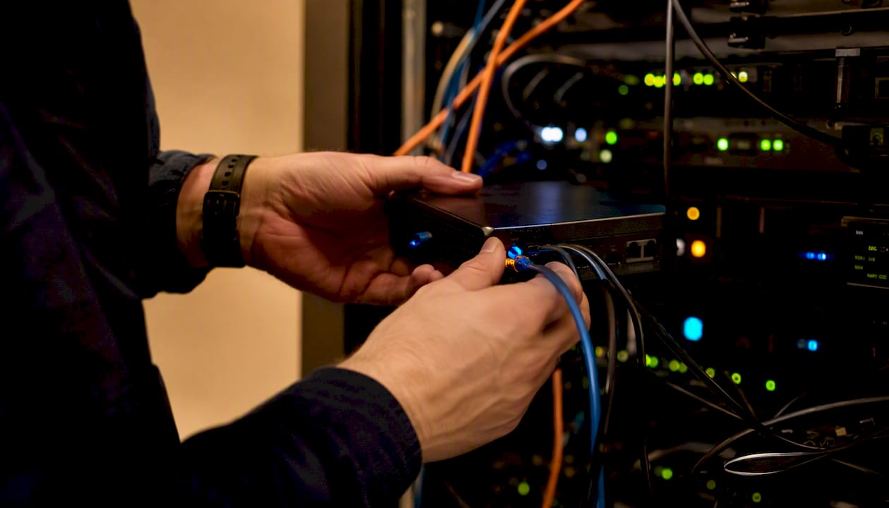 Hands installing network monitoring device in server rack