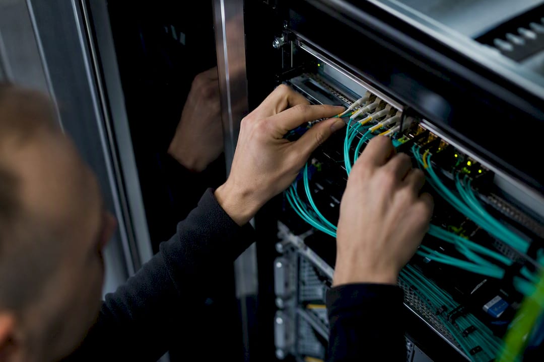 Hands connecting fiber optic cables in server room