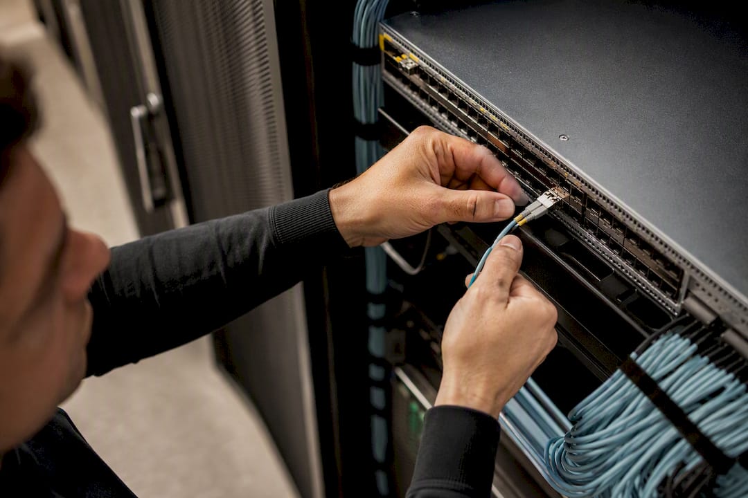 Hands connecting fiber optic cable in data center
