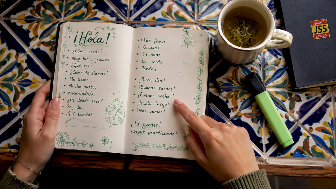 Hands holding notebook with Spanish phrases