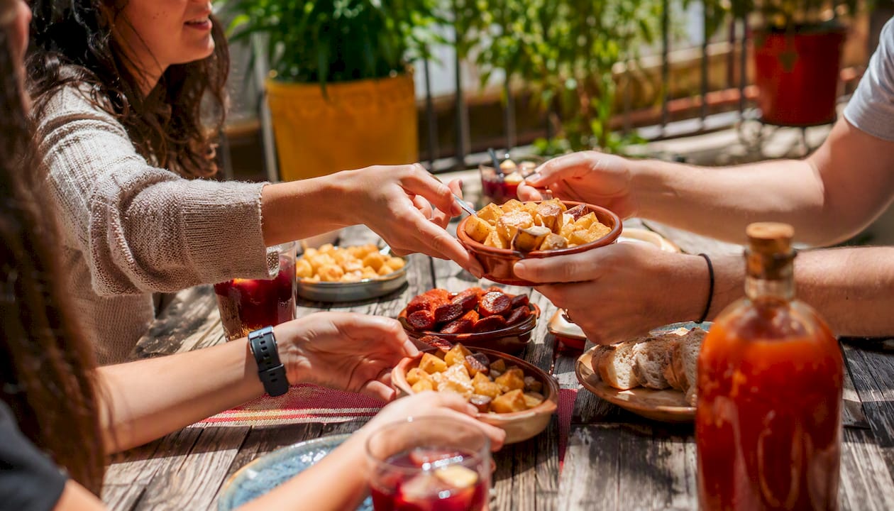 Hands sharing Spanish lunch dishes outdoors