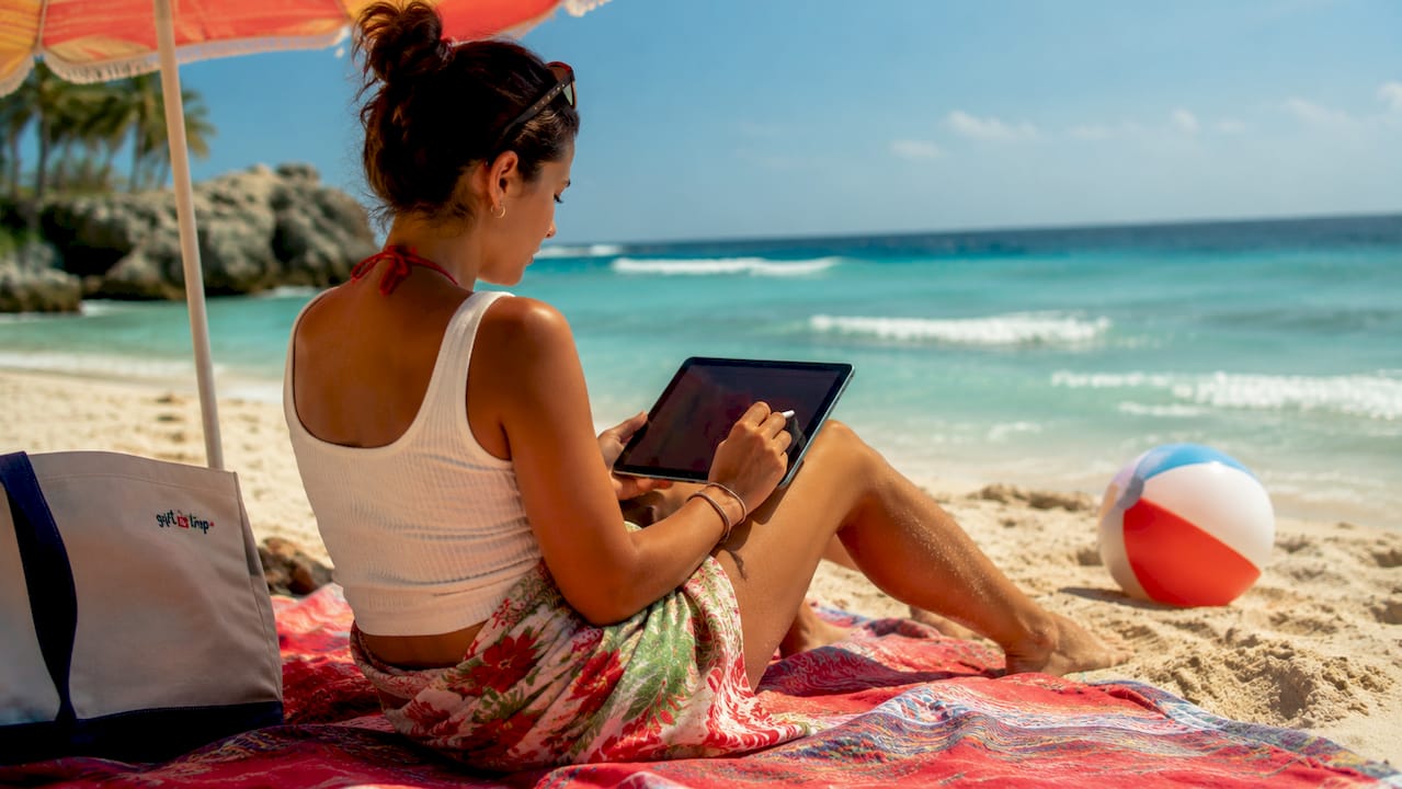 milestone celebration gifting process: your 2026 guide 3 young woman checking gift budget on tablet at beach