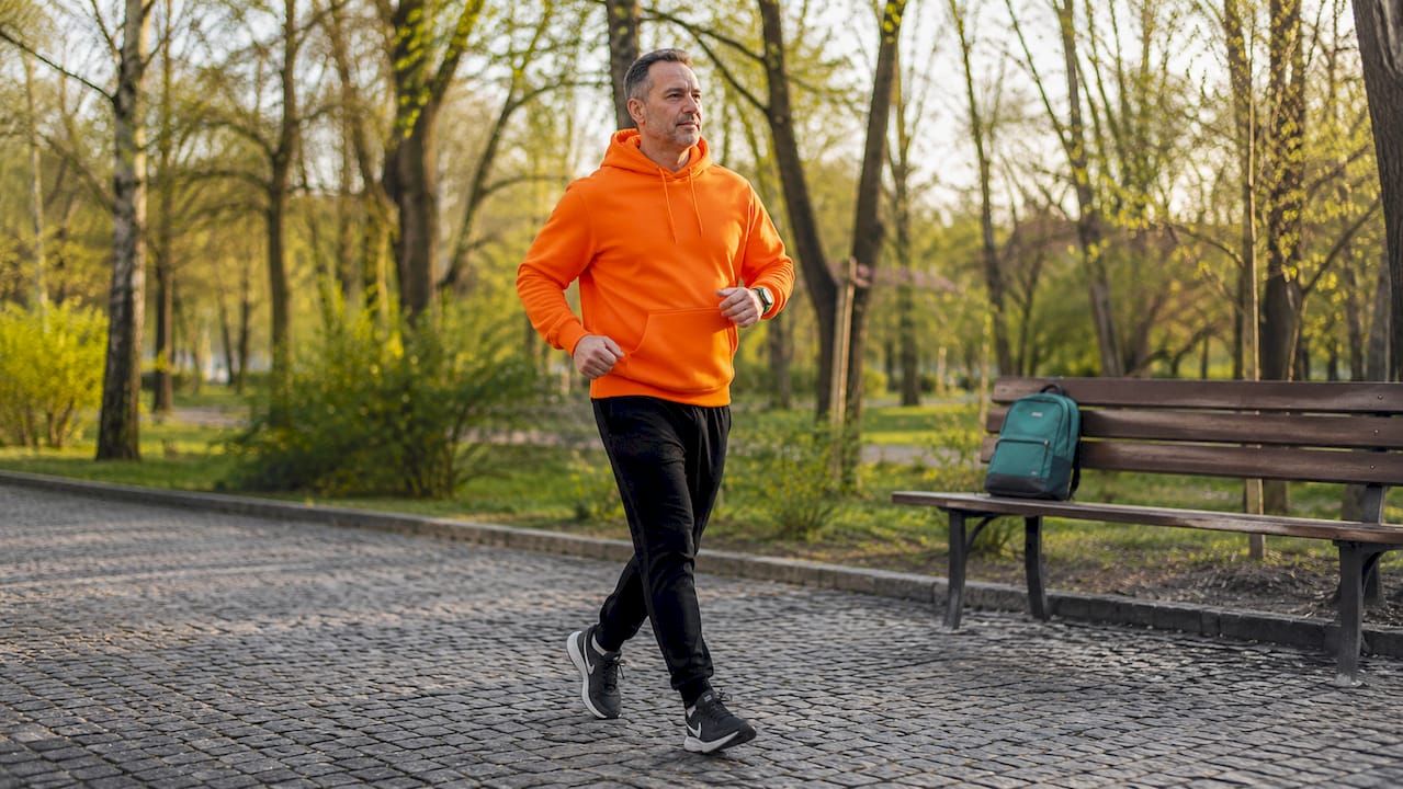 Un bărbat face mișcare în parc, mergând pentru a-și îmbunătăți sănătatea metabolică.