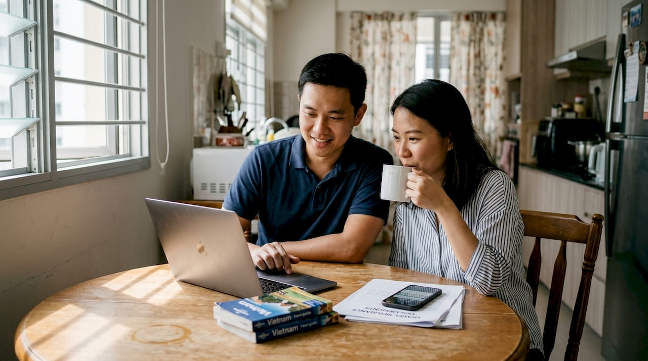 Singaporean couple planning Vietnam travel at kitchen table