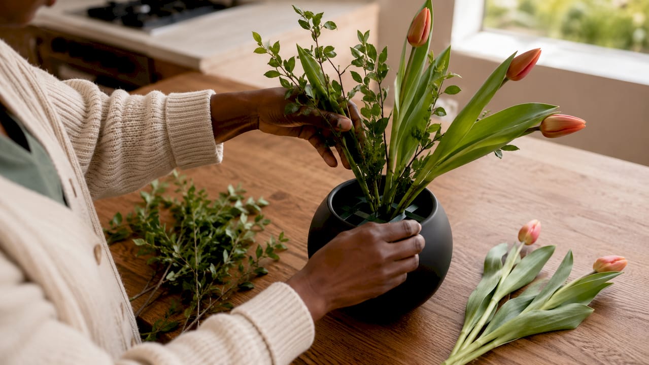 Close-up hands arranging odd-numbered flower stems