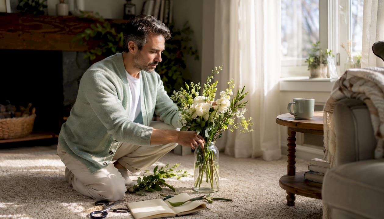 Man arranging subscription flowers at home kitchen table