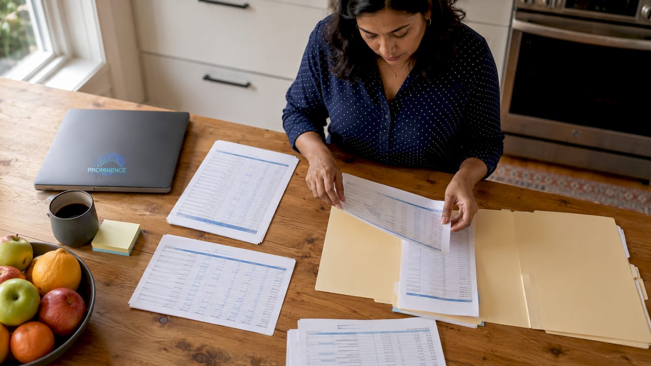 Woman organizing printed account list at desk