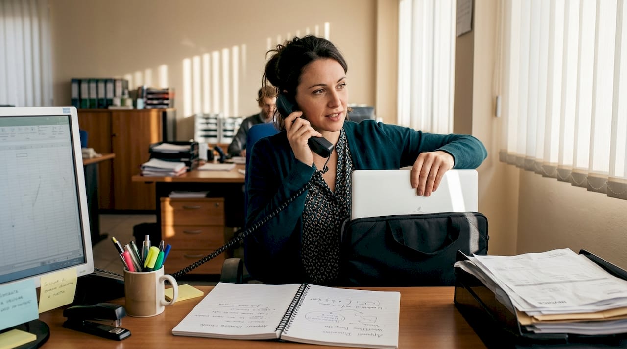 Un impiegato torna alla propria scrivania e apre con cura il portatile appena riparato, pronto a rimettersi al lavoro.