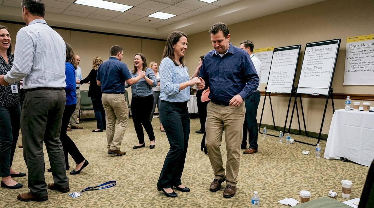 Colleagues partner dancing in conference room