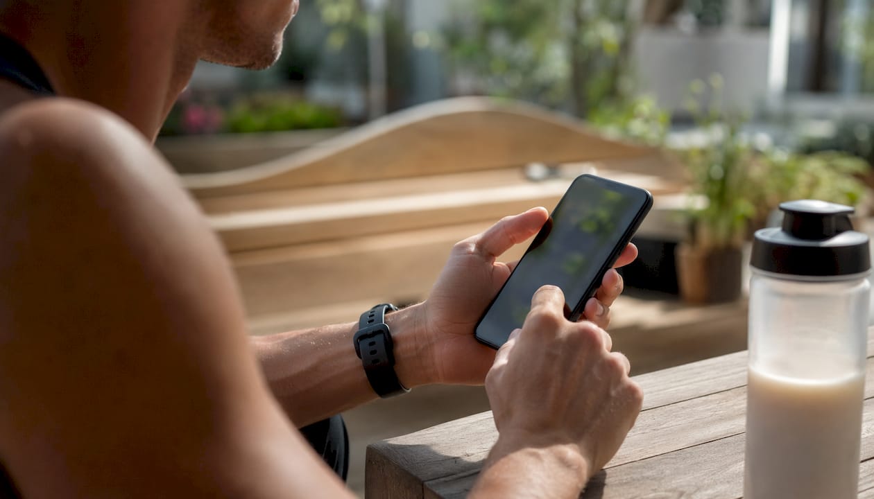 Jemand nutzt im Fitnessstudio eine App zur Trainingsdokumentation auf dem Smartphone.