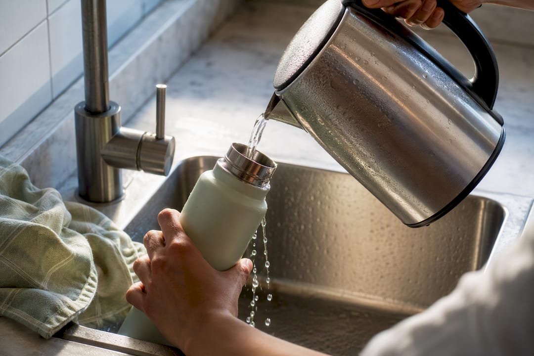 Die Trinkflasche wird mit heißem Wasser ausgespült