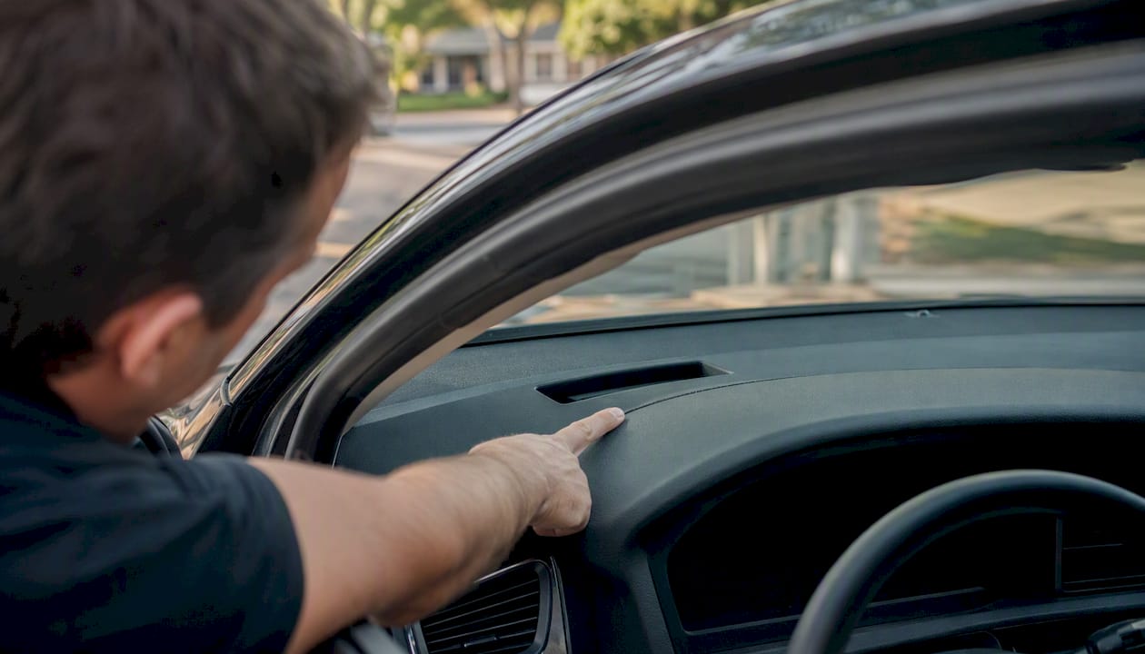 Hand pointing to VIN on car dashboard