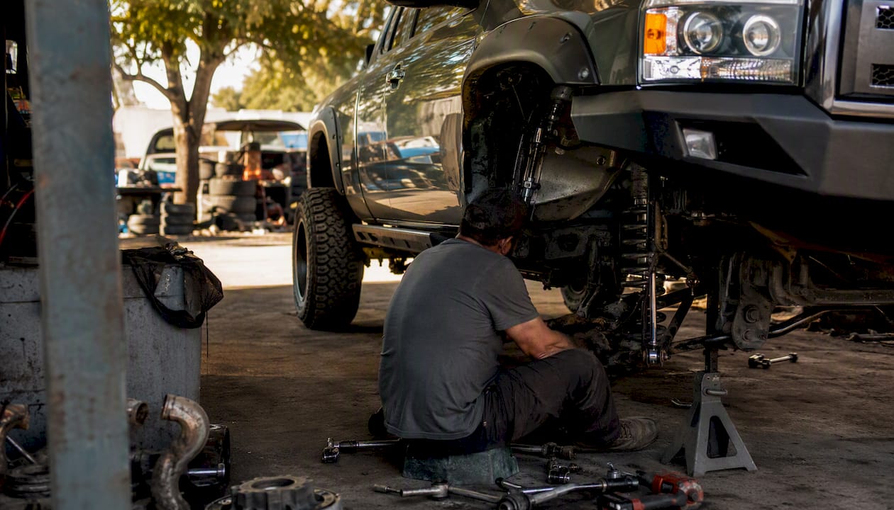 Partial view of pickup truck suspension being modified