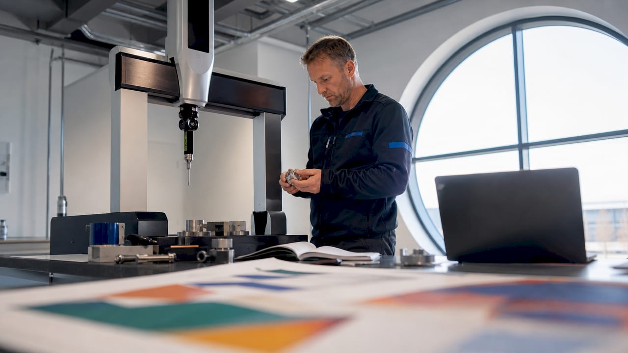 En tekniker genomför mätning av en komponent med hjälp av en CMM-maskin ute på fabriken.