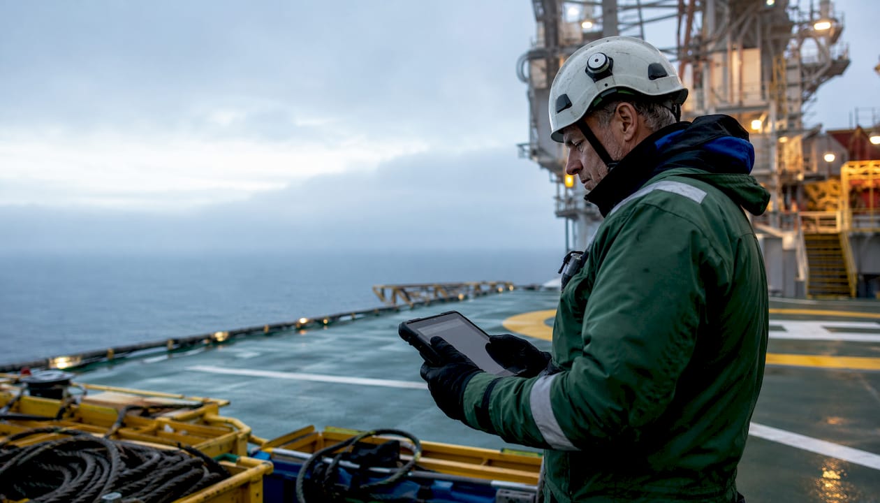 En offshoretekniker genomför mätningar och inspektioner med hjälp av en surfplatta ute på plattformens däck.