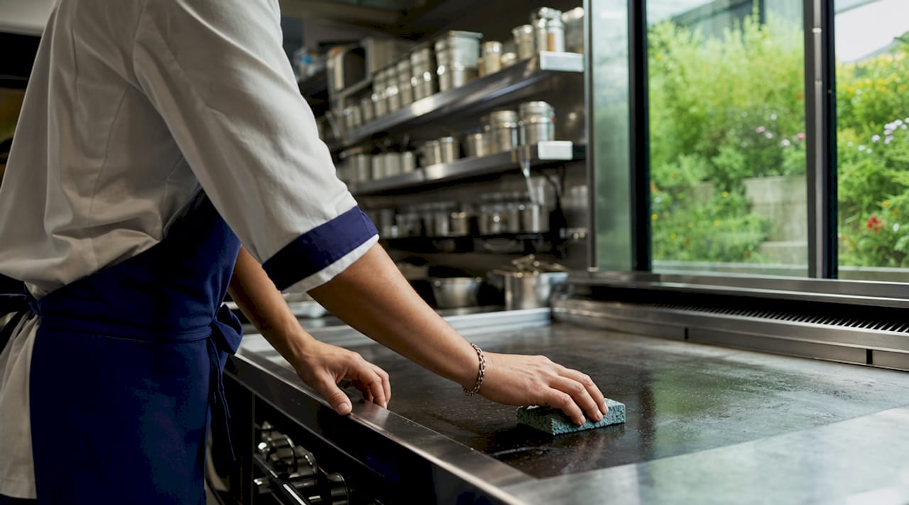 Hands cleaning stainless steel commercial range