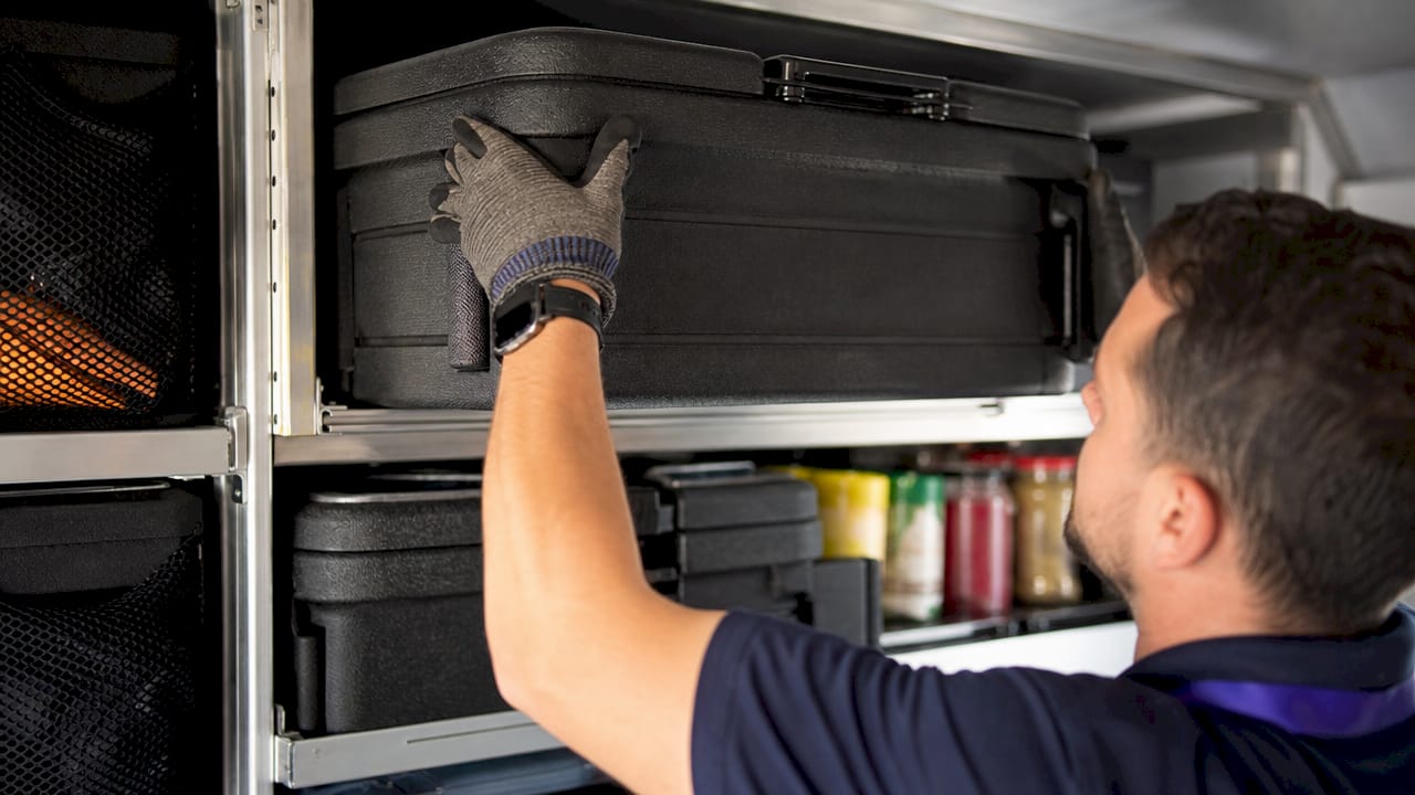 Hands retrieving food container from vertical storage