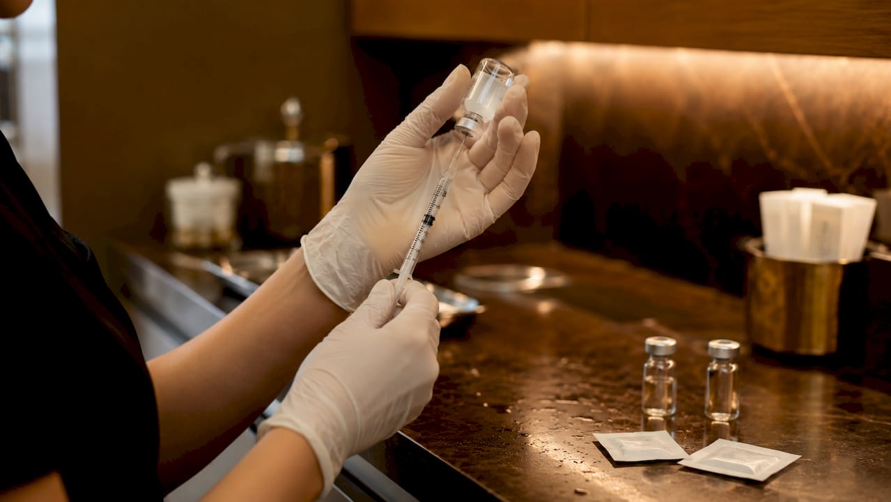 Hands preparing syringe for cosmetic injection
