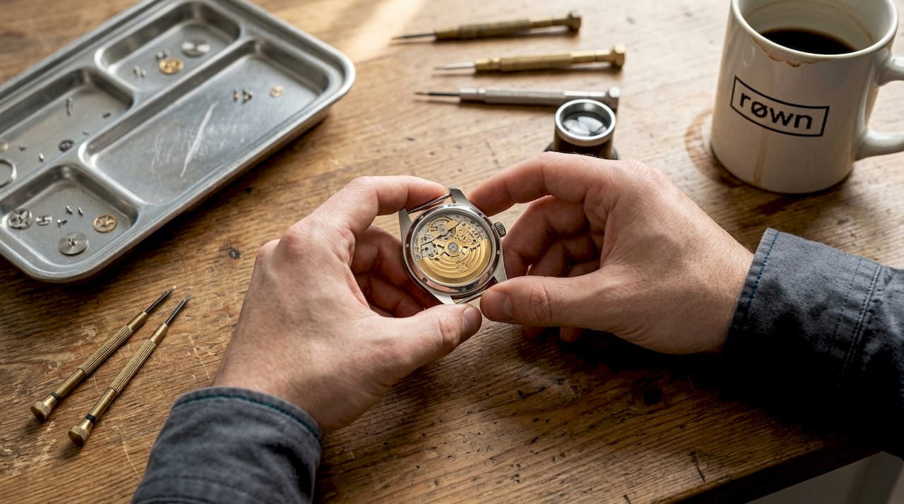 Hands inspecting mechanical watch movement