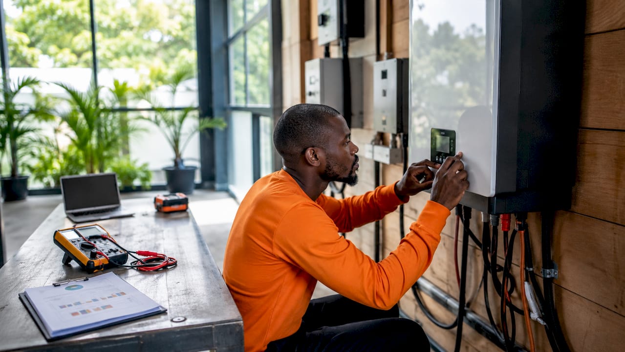 Hands adjusting solar inverter controls indoors