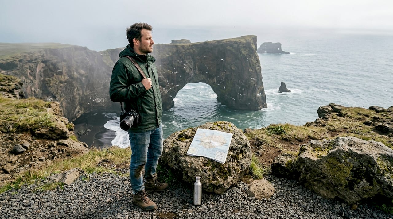 Photographe en pleine séance devant l’arche spectaculaire de Dyrhólaey, en Islande.
