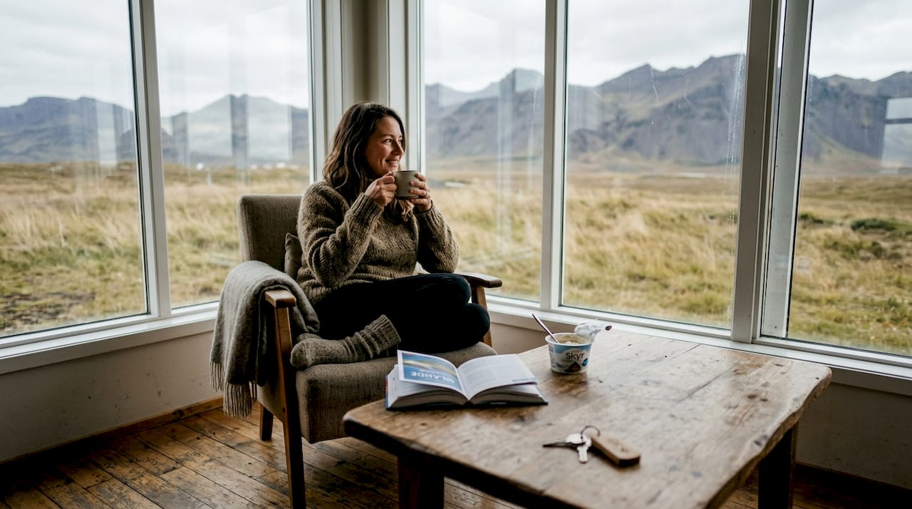 Un voyageur profite d’un moment de détente dans une maison d’hôtes islandaise, face à un panorama naturel à couper le souffle.