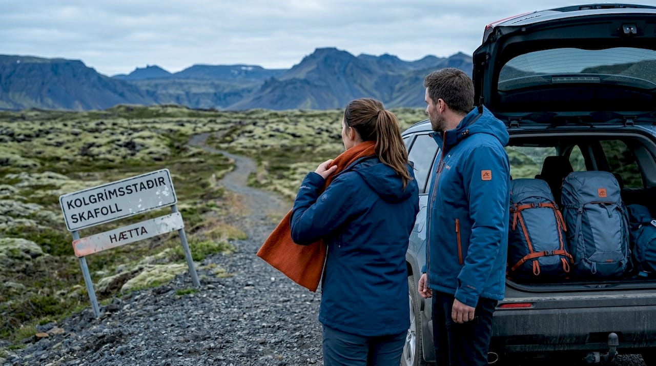 Couple exits SUV near remote Icelandic landscape