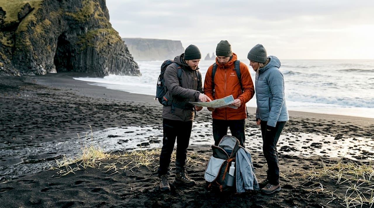 Des randonneurs consultent leur itinéraire sur la célèbre plage de sable noir de Vík.