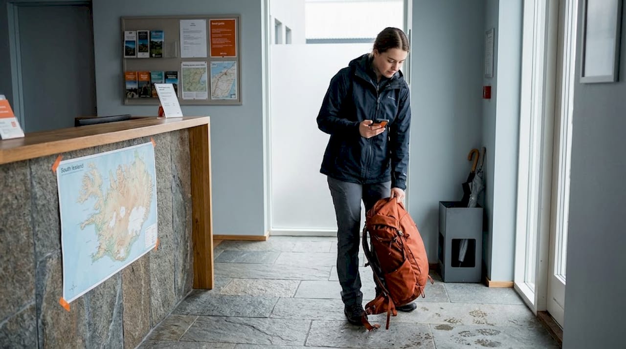 Traveler entering hostel lobby checking phone