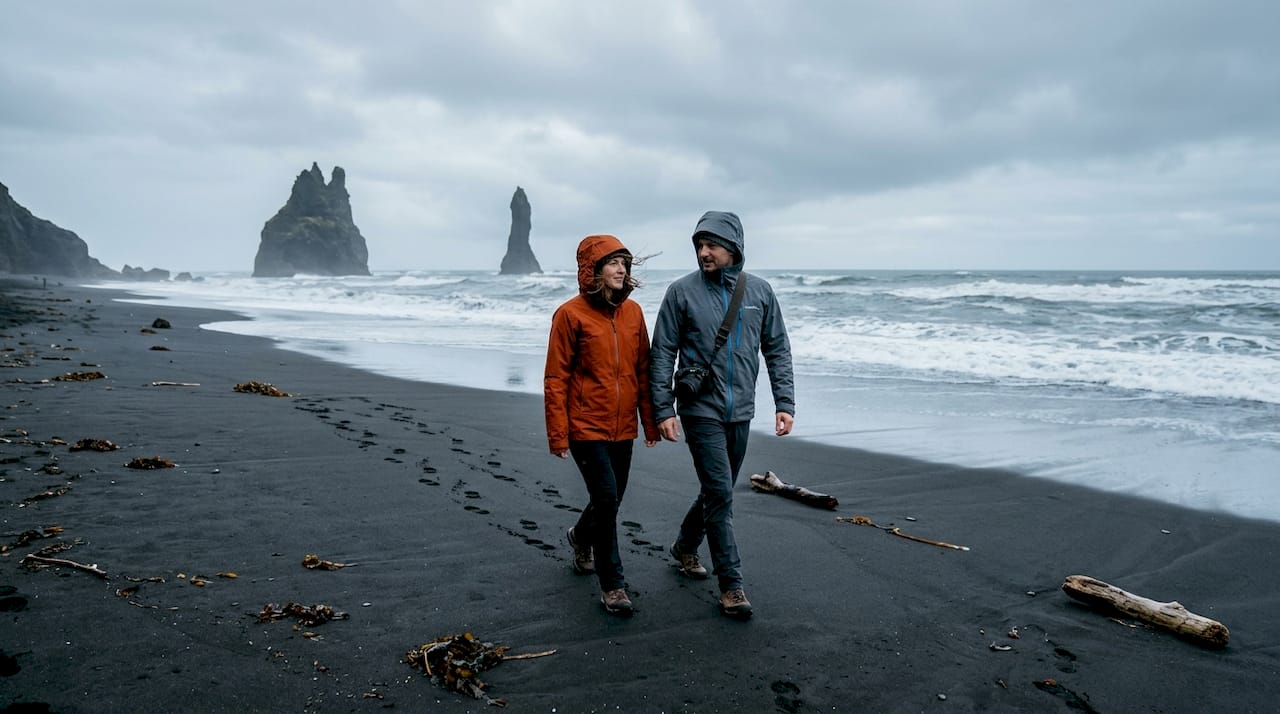 Un grupo de viajeros recorre la playa de arena negra de Reynisfjara, disfrutando del impresionante paisaje.