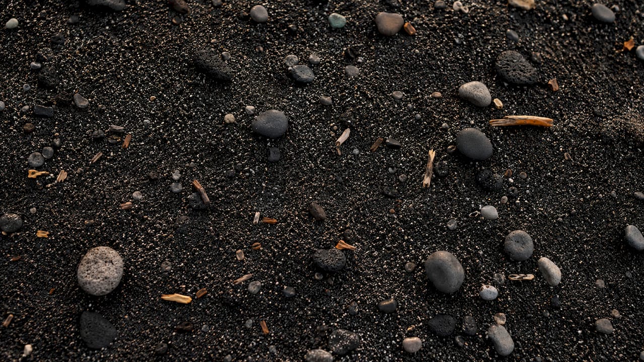 Close-up of wet black basalt sand texture and grains